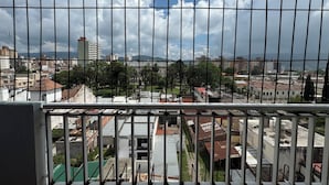 A view through a metal fence of a cityscape with buildings, trees, and a clear sky. - Hotel Quebrada de Humahuaca (San Salvador de Jujuy)