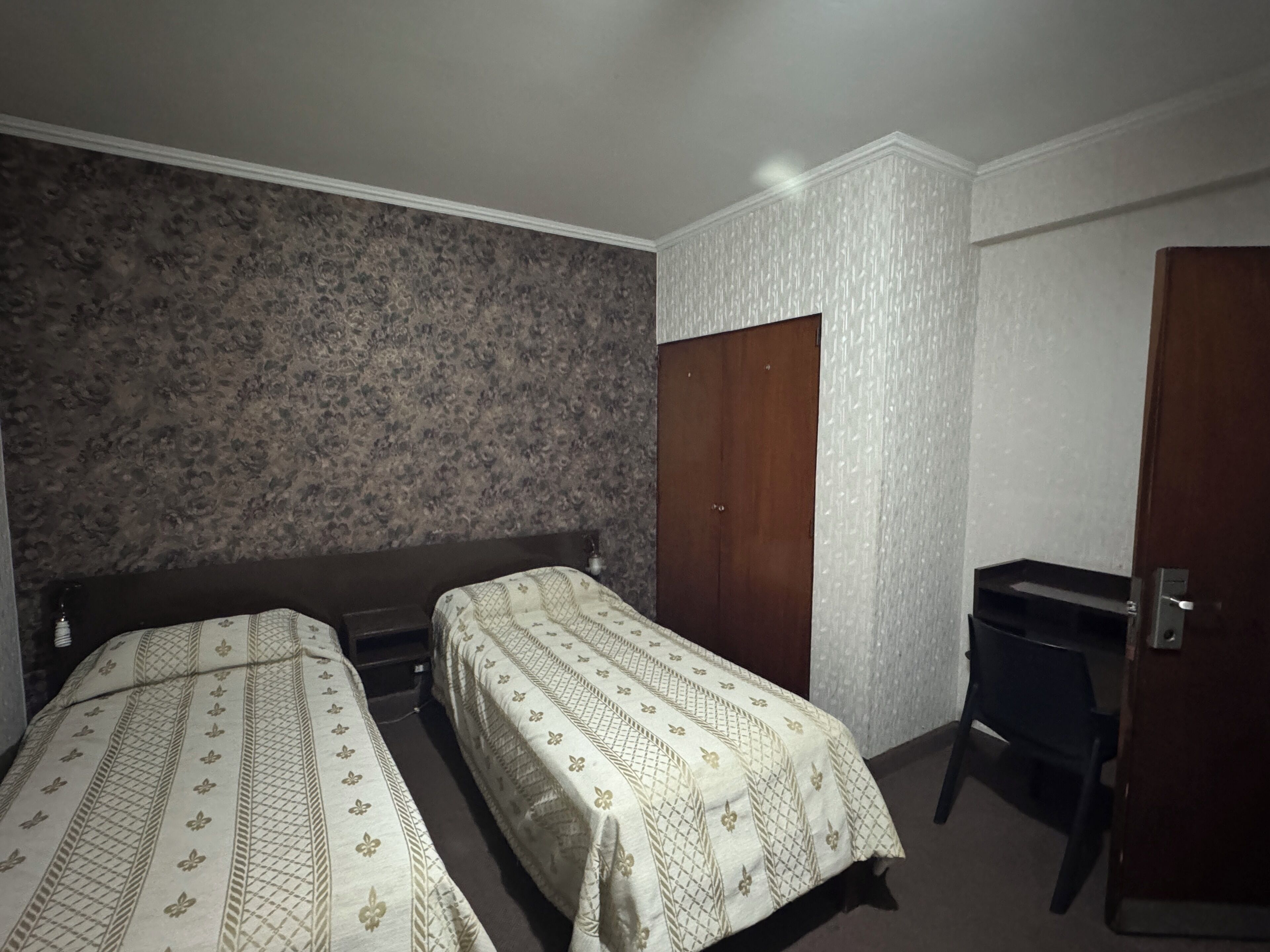 A room with two beds, a desk, and a wardrobe.