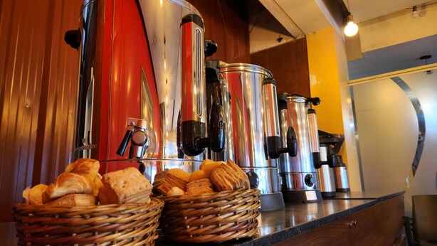 A coffee station with multiple espresso machines and baskets of bread. - Hotel Quebrada de Humahuaca (San Salvador de Jujuy)