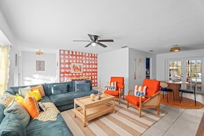 Ein Wohnzimmer mit einer Couch, Sesseln, einem Couchtisch und einem Essbereich mit Tisch und Stühlen.