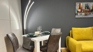 A dining area with a white table, grey chairs, and a yellow sofa. - Cozy bright apartment centrally located with balcony and parking space (Bayreuth)