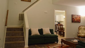 Un salon avec un canapé vert, une table basse et un escalier.