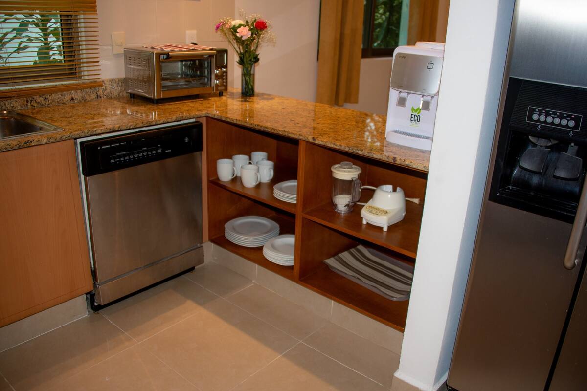 A modern kitchen with a dishwasher, microwave, coffee maker, and a refrigerator.