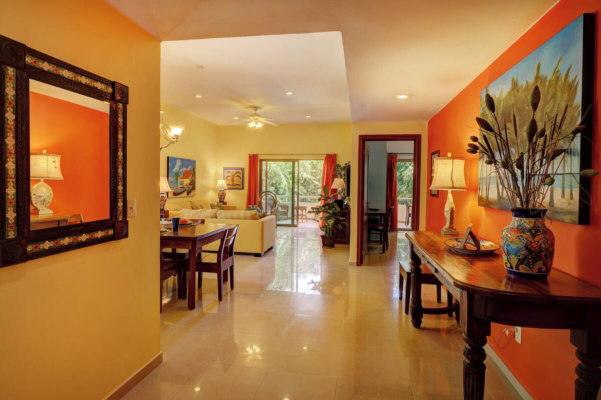 A spacious living area with a dining table, sofas, and a large painting on the wall.