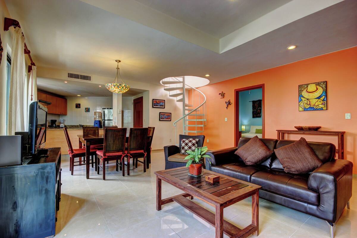 A modern living room with a sofa, coffee table, and dining area.