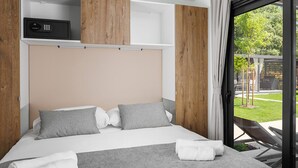 Un dormitorio moderno con una cama grande, almohadas a cuadros, una manta gris y toallas enrolladas.