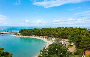A coastal beach area with a sandy shore, clear blue water, and dense green trees. - Awesome home in Umag with swimming pool (Umag)