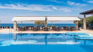 Zona piscina con area relax coperta e vista sul mare.
