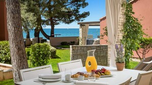 Una tavola apparecchiata per la colazione con vista sul mare, un muro in pietra e una pianta in vaso.