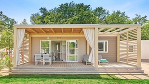 Una terraza de madera con zona de estar cubierta, una mesa y sillas.