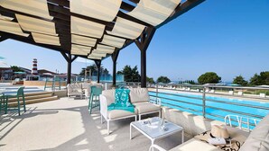 Un espace piscine extérieur avec des chaises longues, une table et une vue sur la mer.