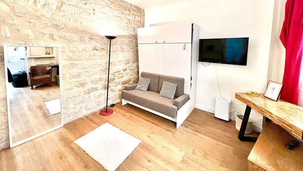 Ein modernes Wohnzimmer mit Steinwand, einer Couch, einem Fernseher und einem Holztisch.