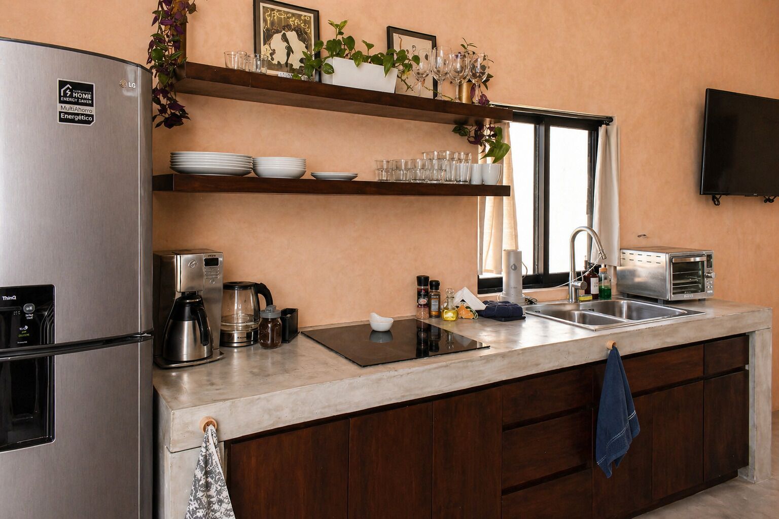 A modern kitchen with a stainless steel refrigerator, coffee maker, toaster, and a sink.