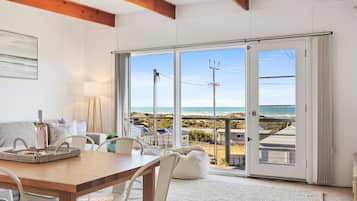A spacious room with a large sliding glass door leading to a balcony with a view of the beach and ocean.