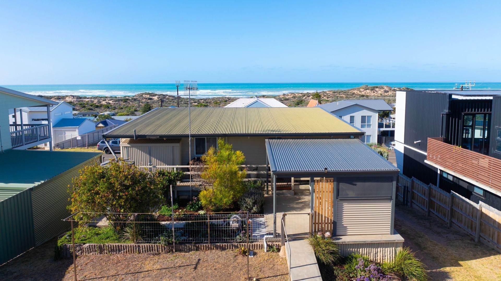 A residential property with a covered patio, a fenced garden, and a view of the ocean.