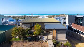 A residential property with a covered patio, a fenced garden, and a view of the ocean.