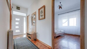 A hallway leading to a bedroom with a bed, a mirror, a framed picture, and a chandelier. - Nice apartment in Delnice with WiFi (Delnice)