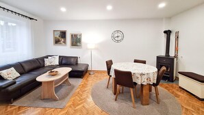 A living room with a sofa, coffee table, dining table with chairs, a fireplace, and a clock on the wall. - Nice apartment in Delnice with WiFi (Delnice)