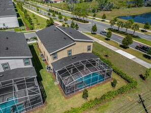 Ein Wohngebiet mit einem Haus, das einen großen, verglasten Poolbereich und gepflegte Rasenflächen sowie Bäume bietet.