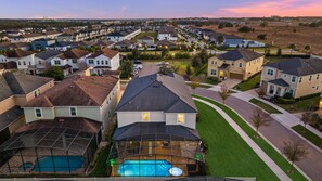 A residential area with houses, a swimming pool, and a well-maintained lawn. - Sun Kissed Oasis at Solara - 9 Bedrooms  -Games, Pool & Togetherness (Kissimmee)