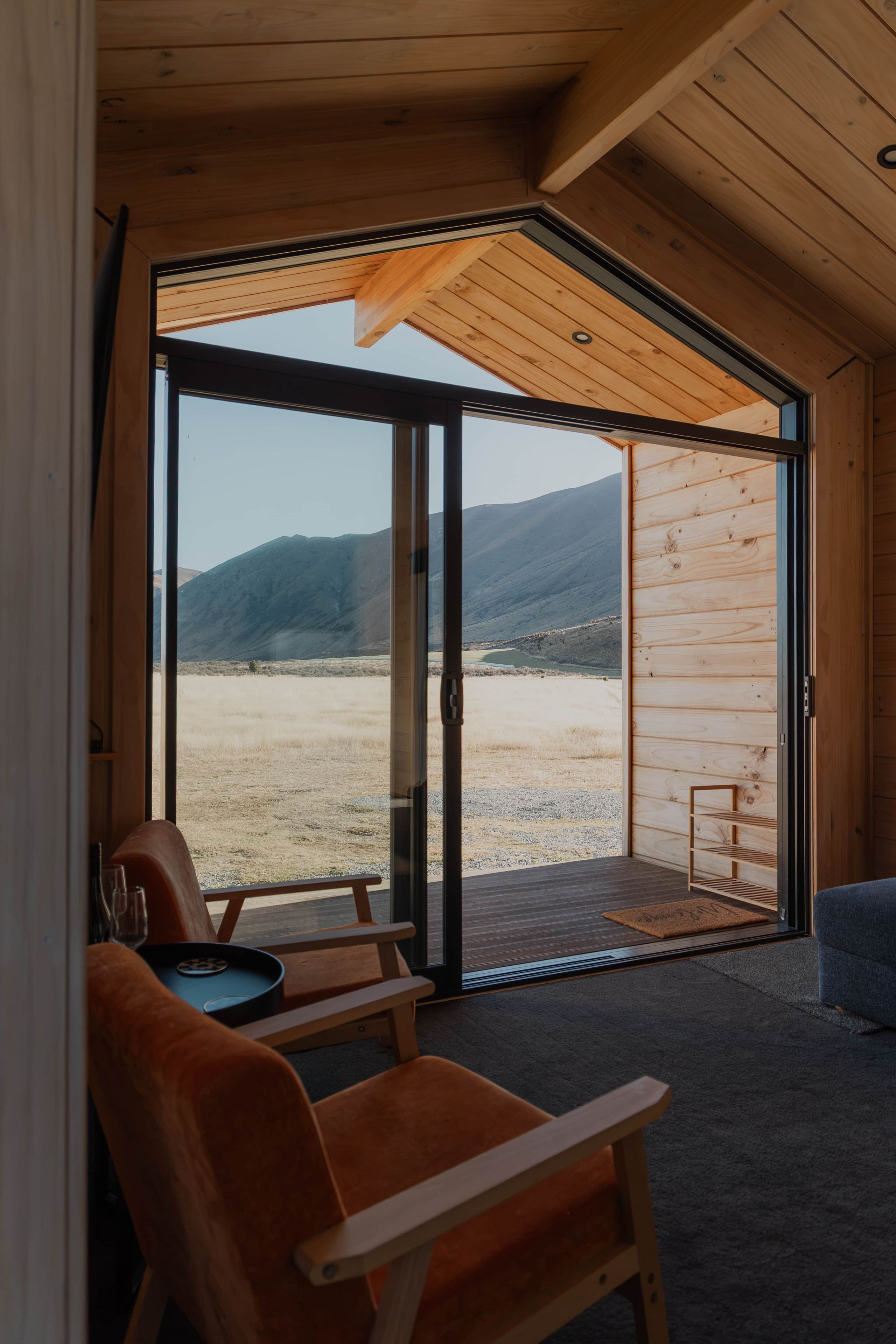 A room with a large sliding glass door leading to an outdoor area with a view of mountains.