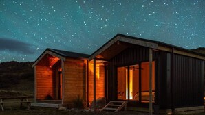A wooden cabin with a large open doorway and a small porch, set against a starry night sky.