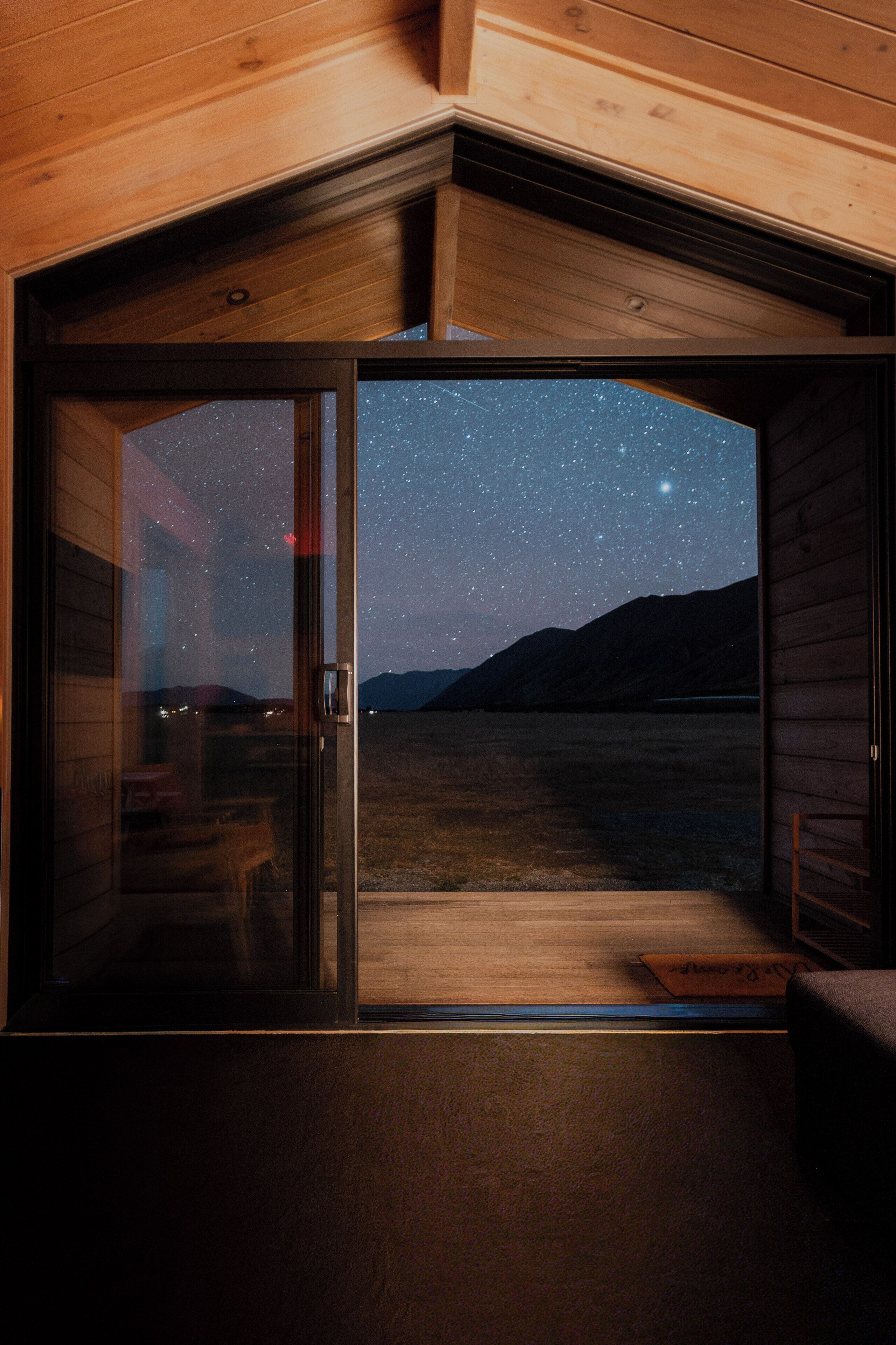 A cabin with a starry night sky visible through a glass door.