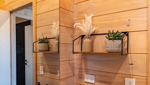 A wooden wall with built-in shelves holding decorative plants and a power outlet.