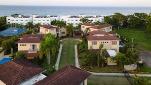 A coastal residential area with multiple houses, a central lawn, and a view of the ocean. - 6 bedroom Villa steps from the beach (Sosúa)