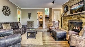 A living room with leather sofas, a coffee table, a fireplace, and a staircase leading to another room. - 2BR/2BA, 2 Fireplaces, Hot Tub, 10 Minutes from Downtown and GSMNP, No Pet Fee! (Gatlinburg)