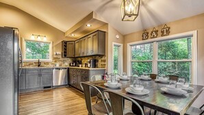 A modern kitchen with granite countertops, stainless steel appliances, and a dining area with a wooden table set for four. - 2BR/2BA, 2 Fireplaces, Hot Tub, 10 Minutes from Downtown and GSMNP, No Pet Fee! (Gatlinburg)