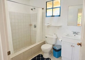 Un baño con ducha, inodoro, lavabo y ventana.