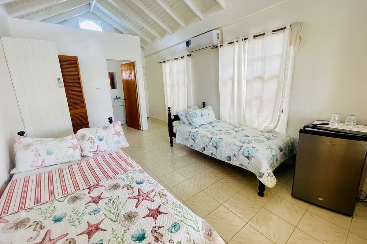 Una camera da letto con due letti, un piccolo frigorifero e un bagno visibile sullo sfondo.