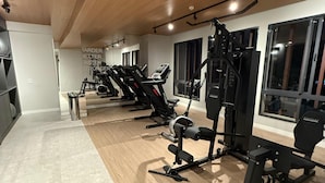 Ein Fitnessstudio mit Laufbändern, Kraftgeräten und einer Spiegelwand.