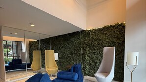 Ein modernes Interieur mit einem blauen Sofa, einem runden Holztisch und zwei Stühlen.