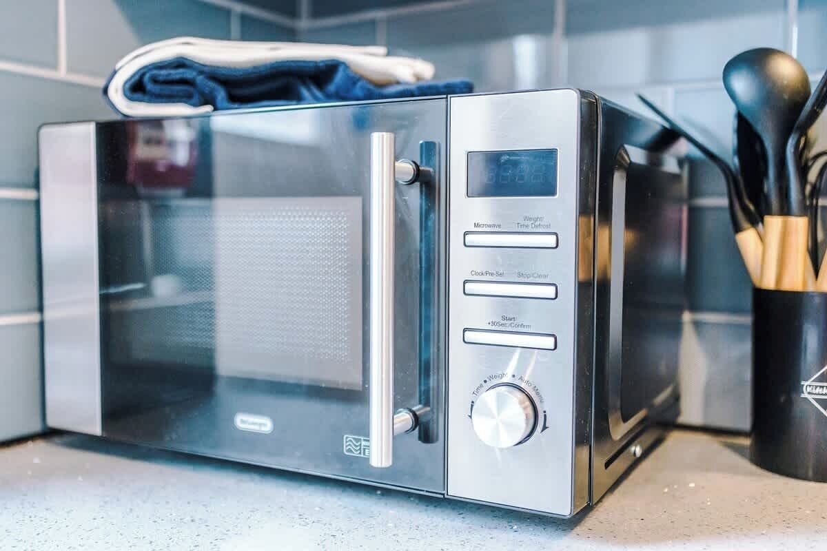 A modern kitchen with a built-in microwave, a digital display, and a stainless steel handle.
