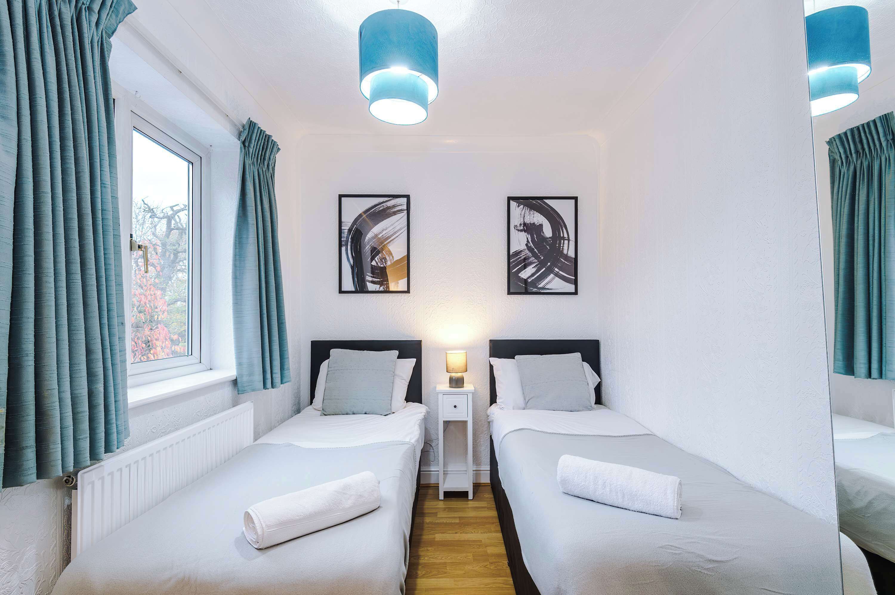 A twin room with two beds, a nightstand, and a window with curtains.