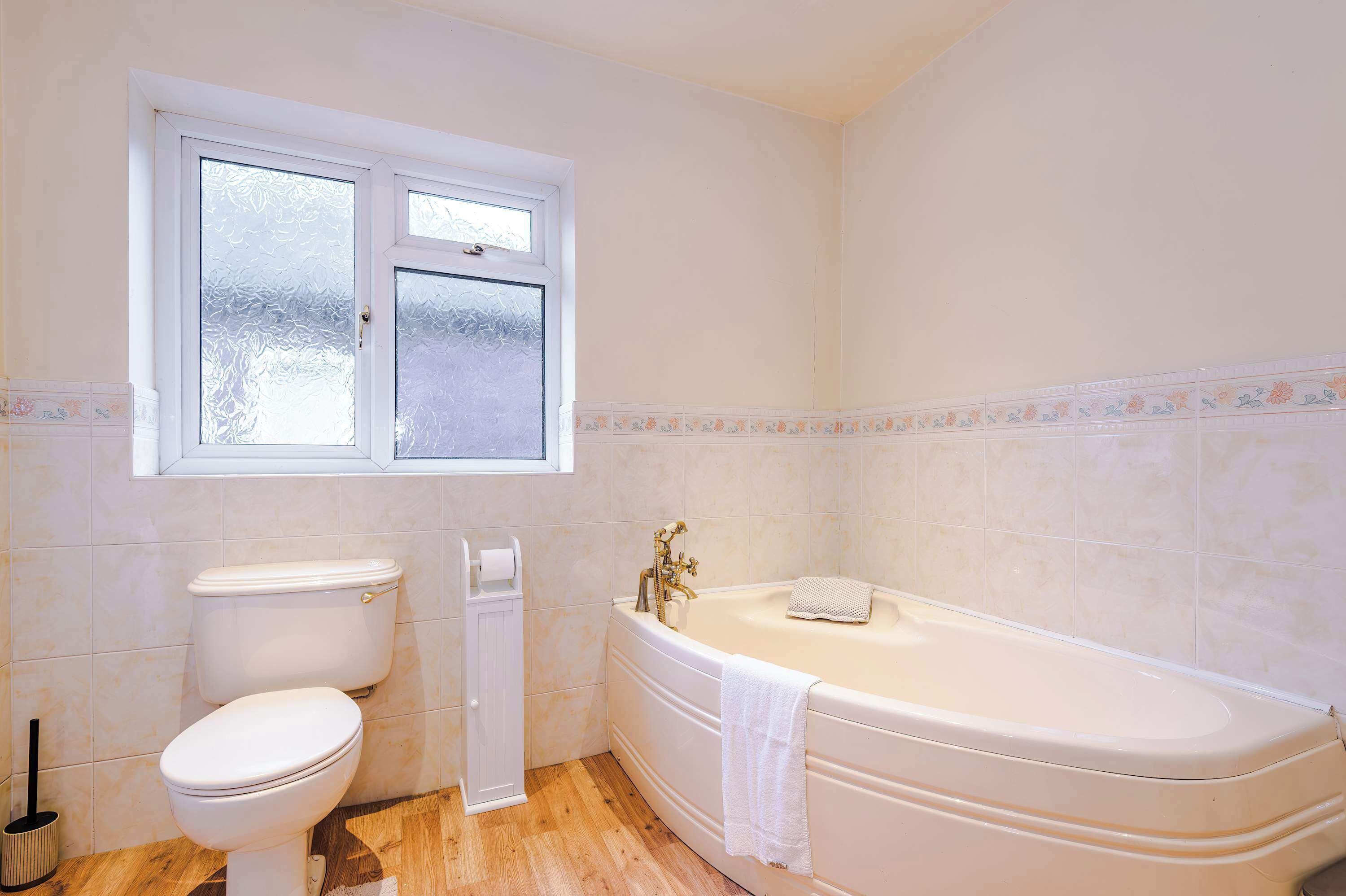 Et badeværelse med toilet, badekar og et vindue.