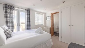 Une chambre à coucher comprenant un lit, une armoire, une salle de bain et donnant sur l’extérieur.