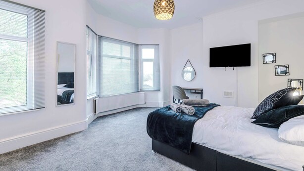 Un dormitorio moderno con una cama grande, televisión y una lámpara de techo original.