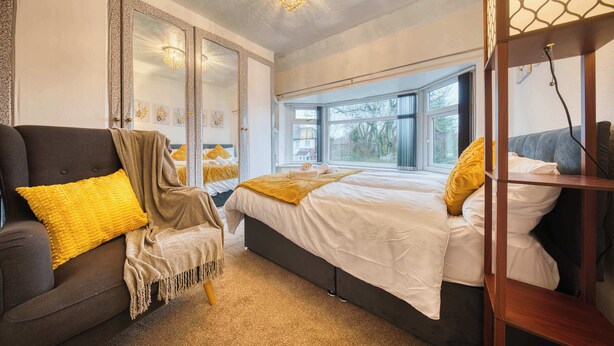 Ein Schlafzimmer mit Bett, Stuhl, Fenster und Spiegel.