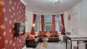 Ein gemütliches Wohnzimmer mit einem Ecksofa, einem kleinen Tisch und einem Fernseher.