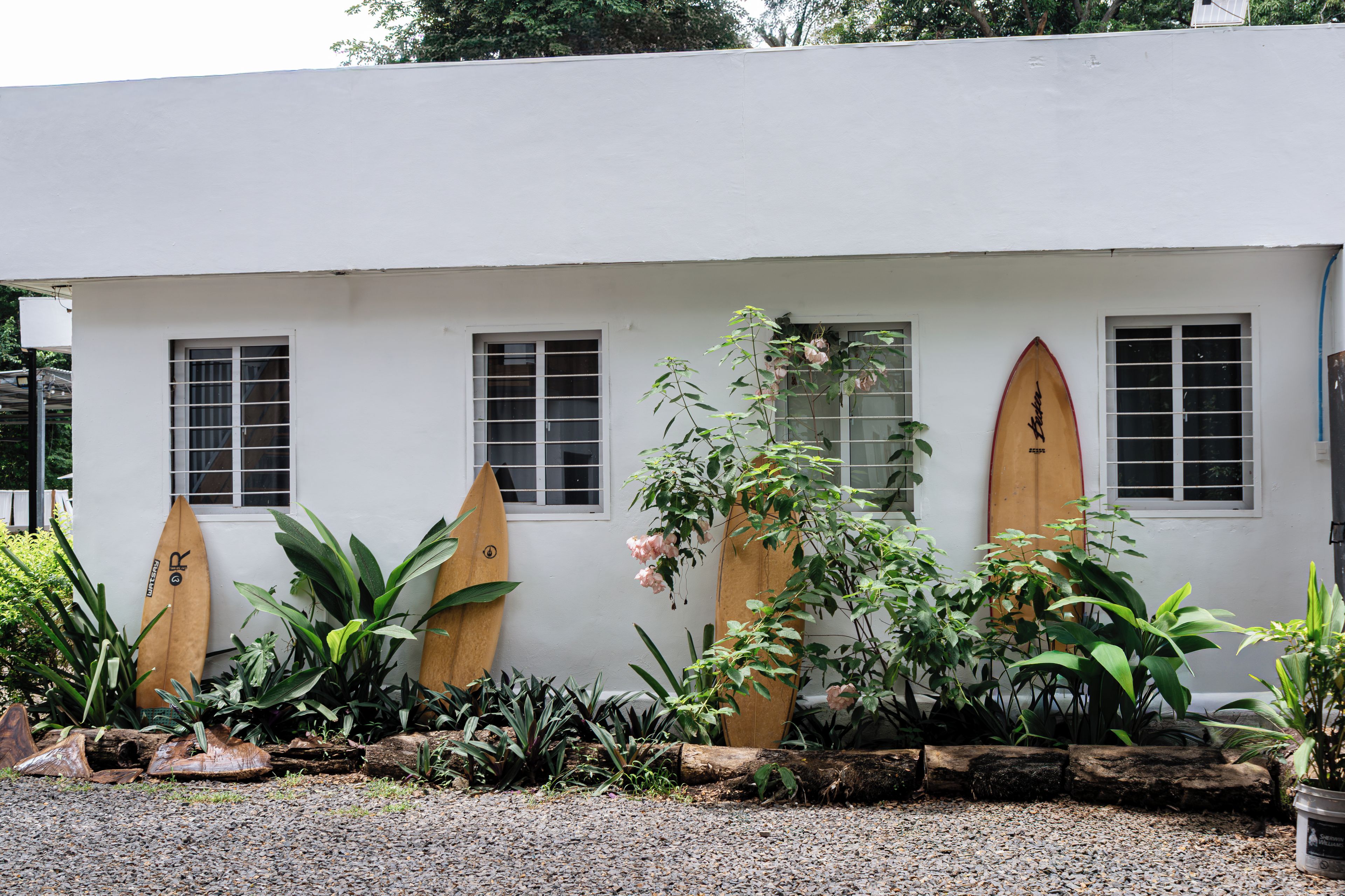 A building with three windows and two surfboards mounted on the wall.