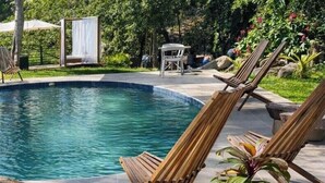 A pool area with wooden lounge chairs and a potted plant. - amalfi surf lodge  (Chiltiupan)