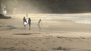 A beach with people walking and carrying surfboards. - amalfi surf lodge  (Chiltiupan)