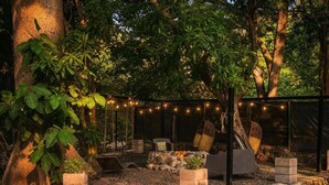 An outdoor patio area with seating, a fire pit, string lights, and a stone wall. - amalfi surf lodge  (Chiltiupan)