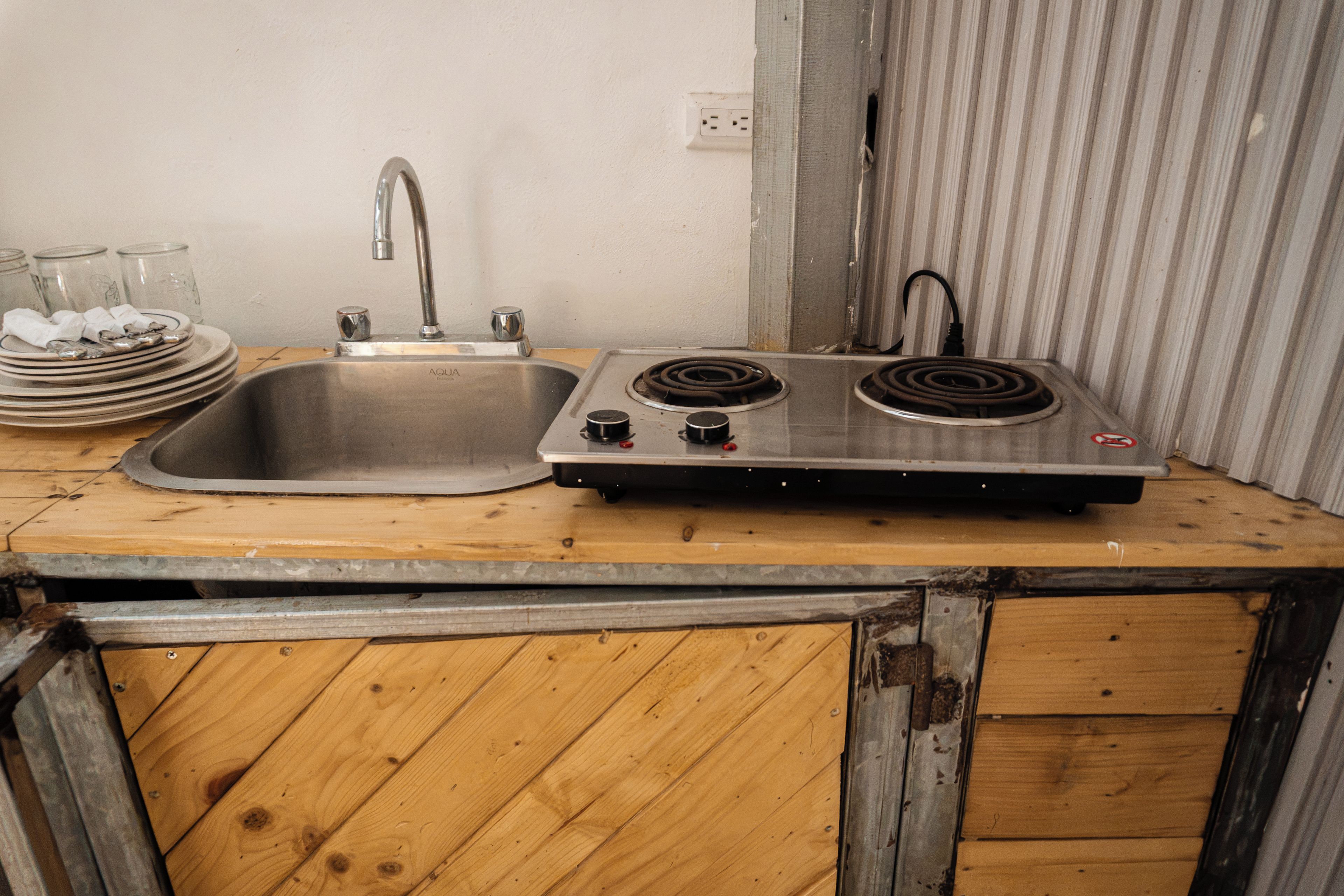 Een keuken met een spoelbak, fornuis en een houten aanrecht.