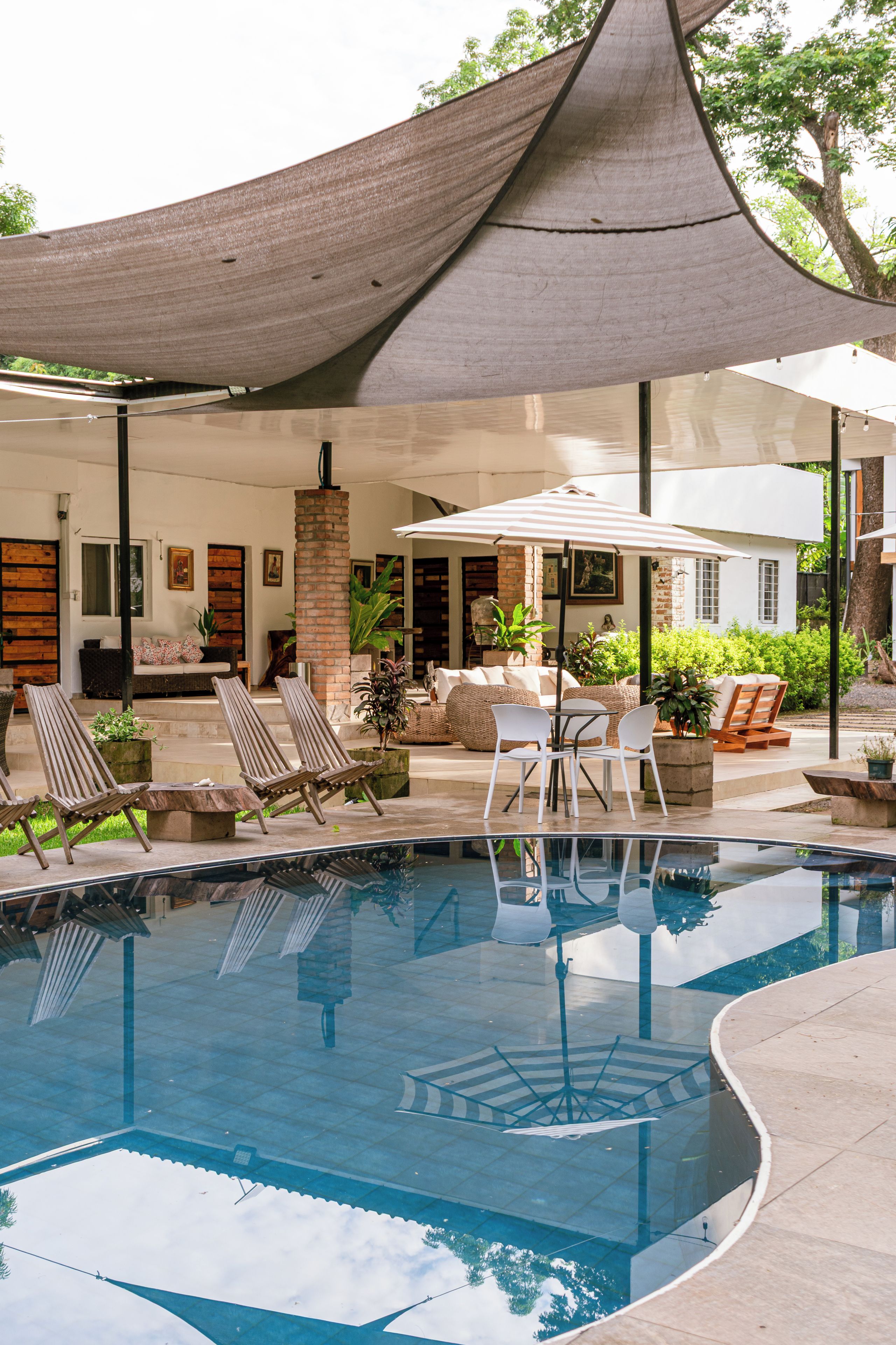 A swimming pool with lounge chairs and umbrellas, surrounded by a covered patio area.