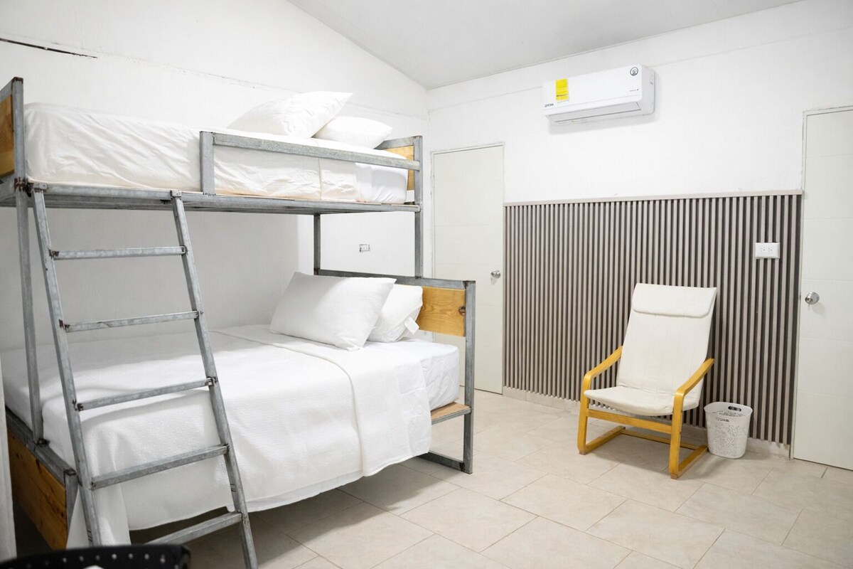 Un lit superposé avec une échelle, une chaise et un radiateur.