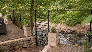 A garden with a gravel path, a metal gate, and a small stream. - amalfi surf lodge  (Chiltiupan)